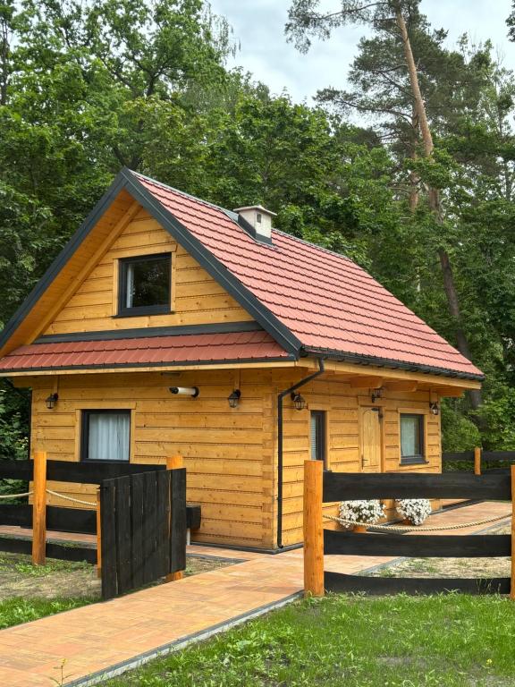 a small cabin with a red roof on a wooden deck at Chata u Drwala Święta Lipka in Święta Lipka
