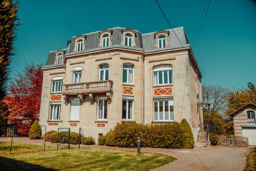 a large brick building with a gambrel roof at La Source de la Scance in Verdun-sur-Meuse