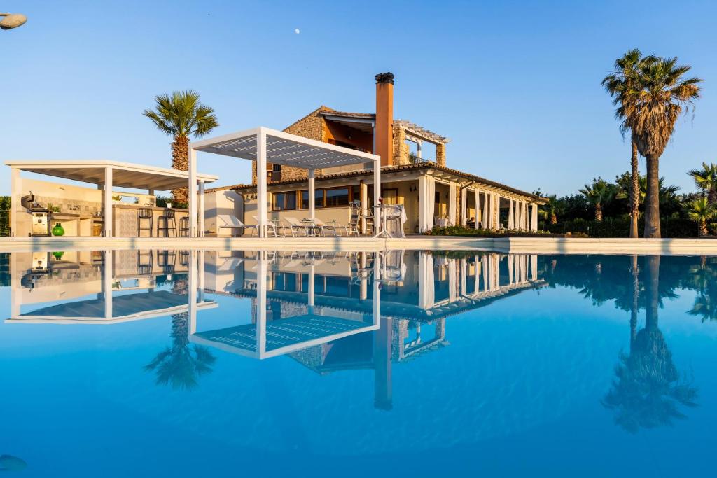 a house with a swimming pool and palm trees at Villa Cielo in Paceco