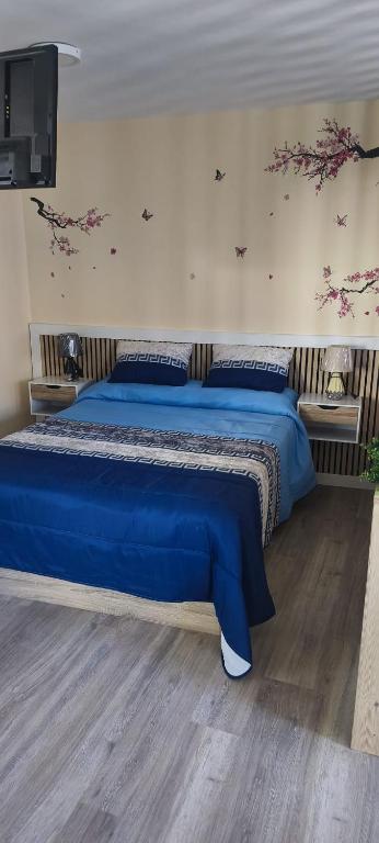 a bedroom with a blue bed with flowers on the wall at O casal in Cambados