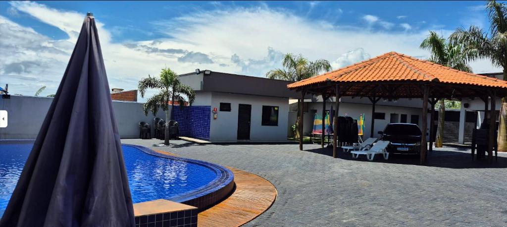 an umbrella and a swimming pool next to a house at Pousada Rancho do Sossego in Céu Azul