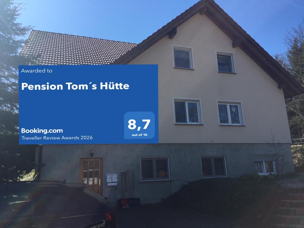 a house with a blue sign in front of it at Pension Tom´s Hütte in Nossen