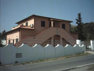 a house behind a white fence with a building at Appartamento in VILLA spazio esterno e posto auto in Rio nellʼElba