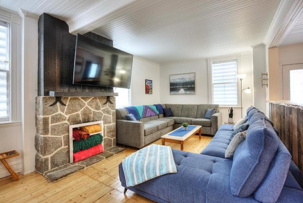 a living room with a blue couch and a fireplace at Country house with SPA, small beach, pool in Mont-Tremblant