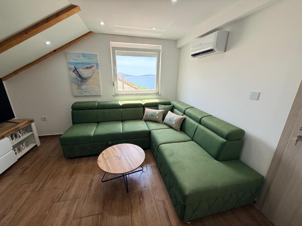 a living room with a green couch and a table at Apartman Lucija 5 in Zubovići
