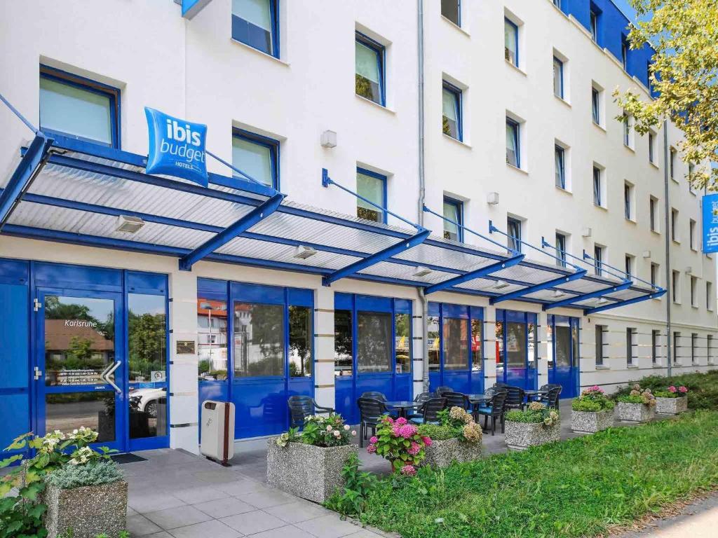 a building with blue doors and chairs in front of it at ibis budget Karlsruhe in Karlsruhe