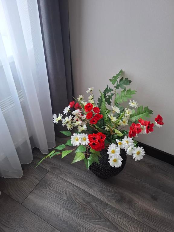 a vase filled with red and white flowers on a floor at Mistera rezidence in Jelgava