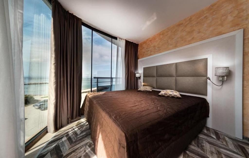 a bedroom with a large bed with a large window at Sun Boutique Pomorie in Pomorie