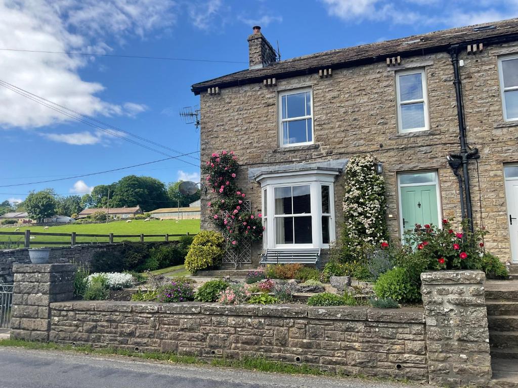 a stone house with a green door and flowers at Dale Grange in Askrigg
