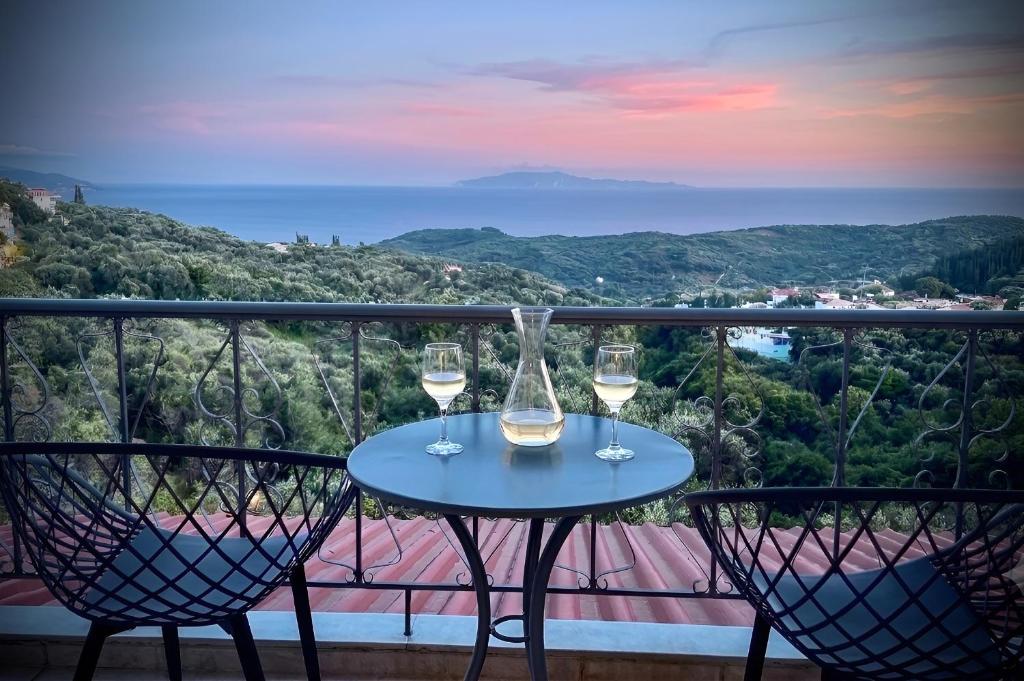 a table with two glasses of wine on a balcony at Anthoussa Rooms in Parga