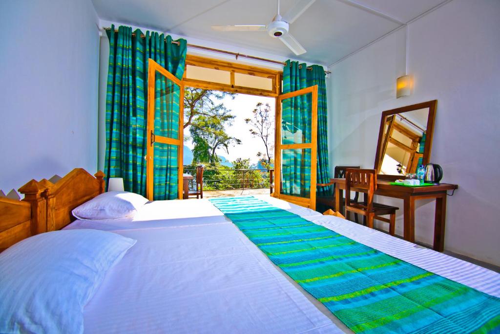 a bedroom with a large bed with a window and a desk at Ella Alpine Resort in Ella