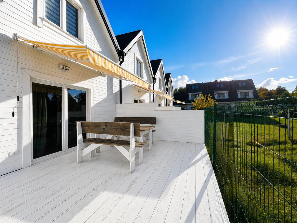 a wooden bench sitting on a deck in front of a house at TuNaChill domki nad morzem w Dziwnowie in Dziwnów