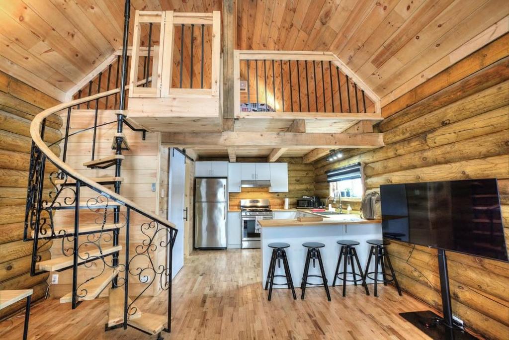 a kitchen with a spiral staircase in a log cabin at Log cabin with SPA, pool, and small beach in Mont-Tremblant