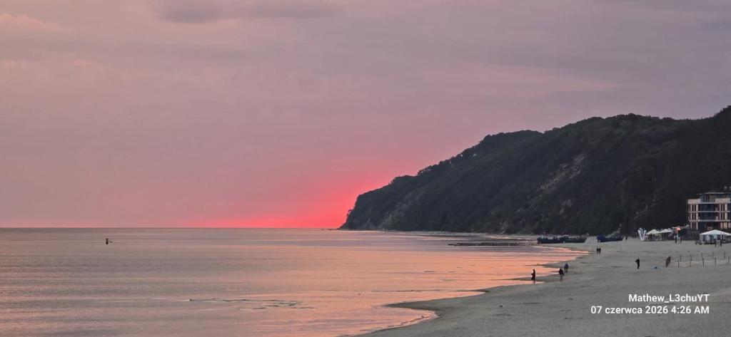 a beach at sunset with people on the sand at Skarb Morza in Międzyzdroje