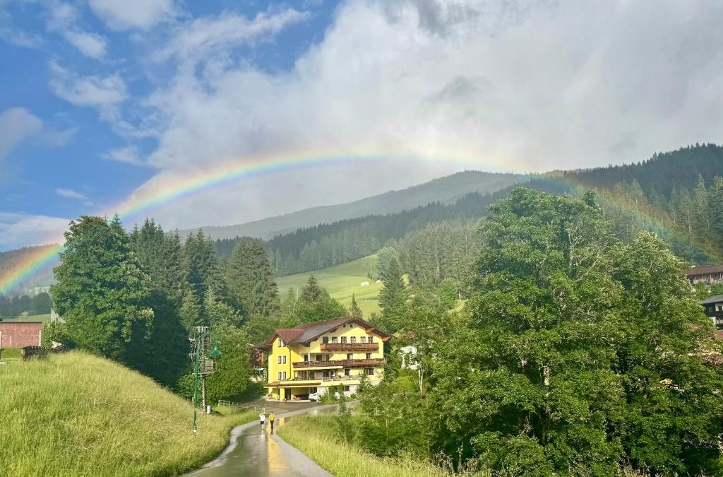 a rainbow in the sky over a house and a road at Julius Appartements & Zimmer in Wagrain