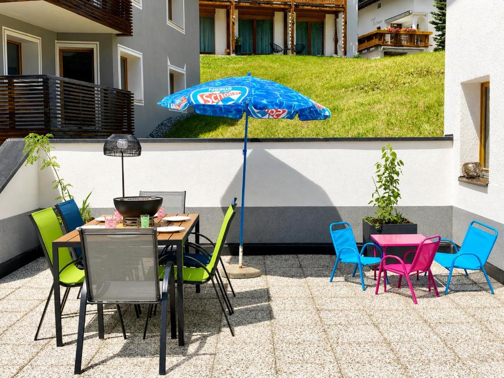 a patio with a table and chairs and an umbrella at Chasa ARLU in Samnaun