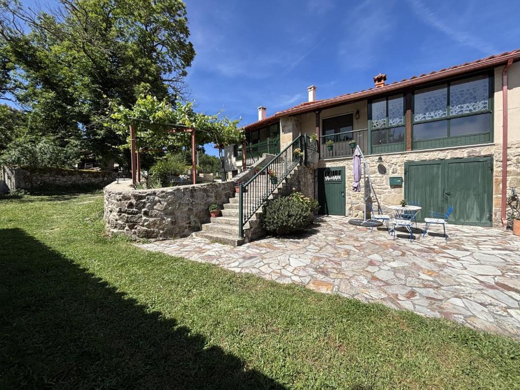 a house with a stone walkway next to a yard at A Casita do Ferreiro in Sober