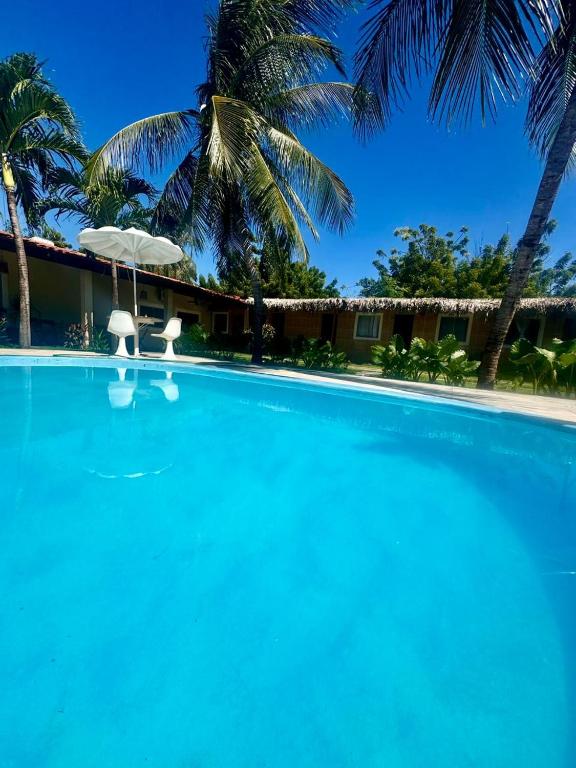 a large blue swimming pool with palm trees in the background at Pousada Marúa Fortaleza in Fortaleza