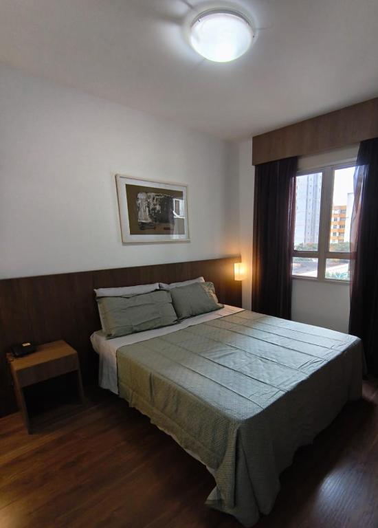 a bedroom with a large bed and a window at Flat Niagara Belo Horizonte in Belo Horizonte