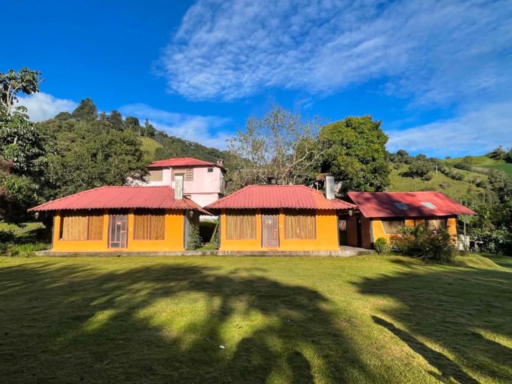 a house in the middle of a grass field at Las Orquídeas Runtun Lodge in Baños