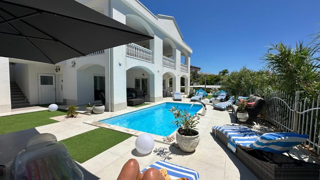 a backyard with a swimming pool and a house at Willa Casa Blanca in Pag