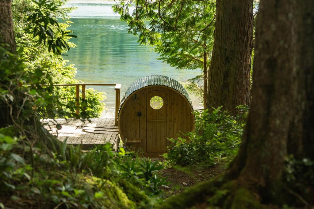 a wooden hobbit house sitting next to a body of water at The Four Cedars in Ucluelet