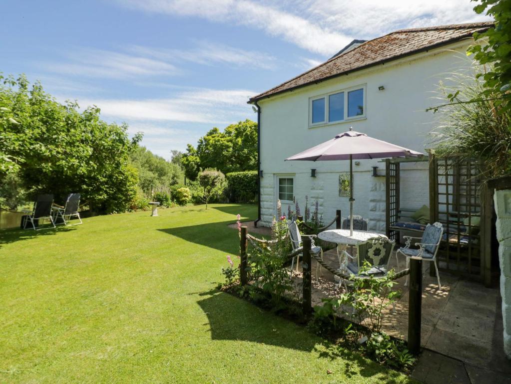 a house with a table and an umbrella in the yard at Severn Bank Lodge in Shrawley