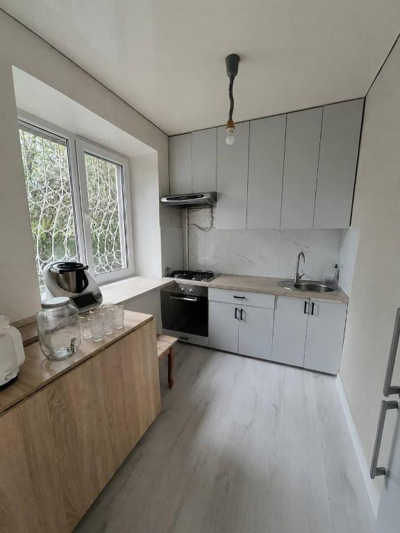 a kitchen with white cabinets and a large window at Дом in Almaty