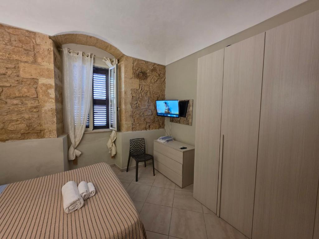 a bedroom with a bed and a tv on a wall at Pasithea House in Marzamemi