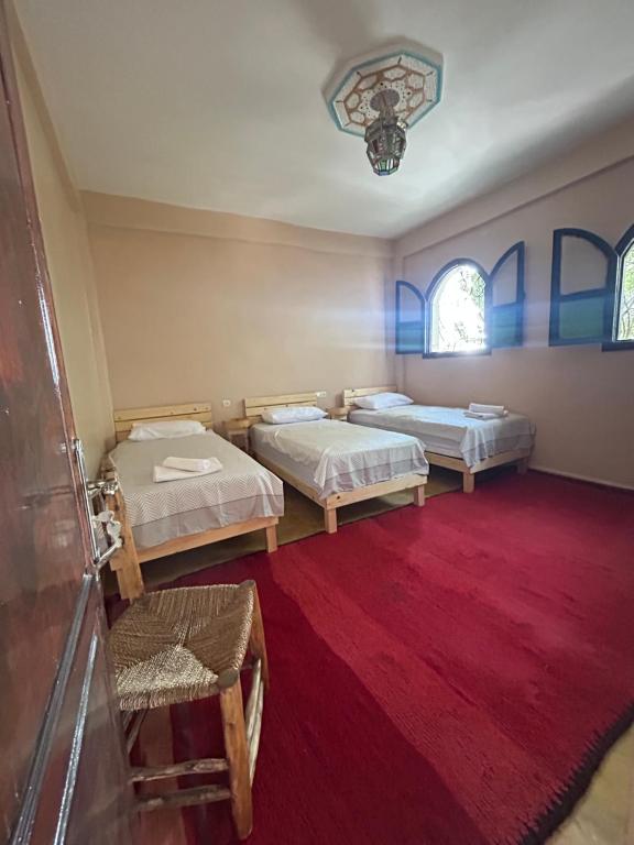 a room with two beds and a red carpet at Sunlight guest house in Taghazout