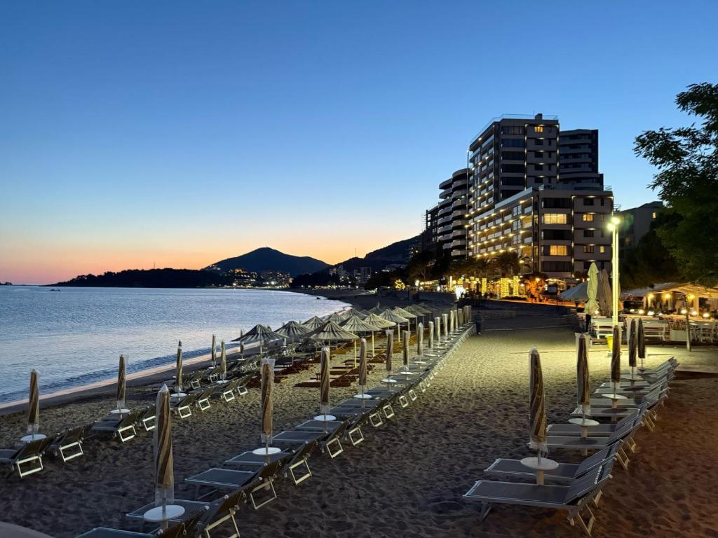 a row of chairs on a beach next to the water at Hotel Obala in Budva