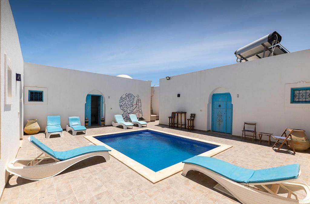 a large swimming pool with chairs and a swimming poolvisor at Dar Ahlem Djerba in El Guecheïne