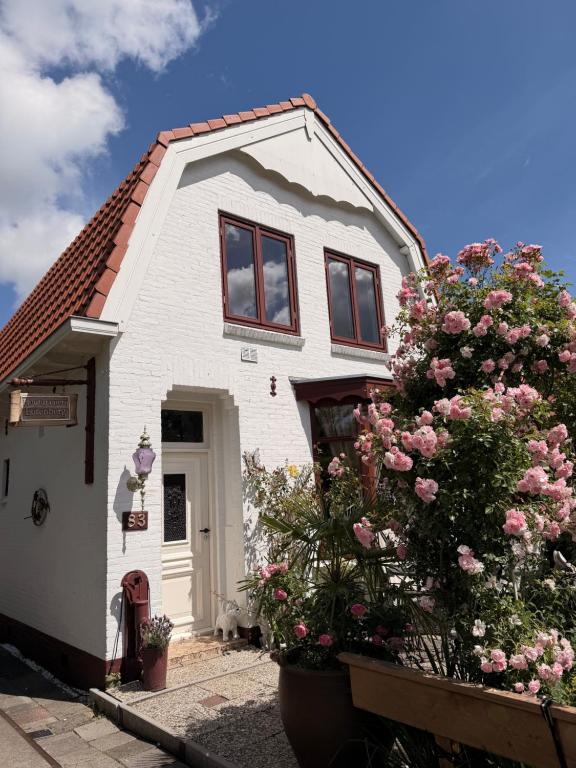 a white house with pink flowers in front of it at B&B The White House in Westzaan