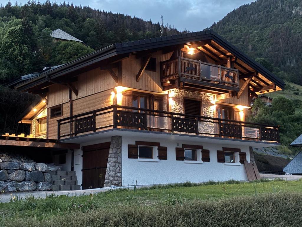 a large wooden house with a balcony at Nid des aiguillettes in Chevenoz