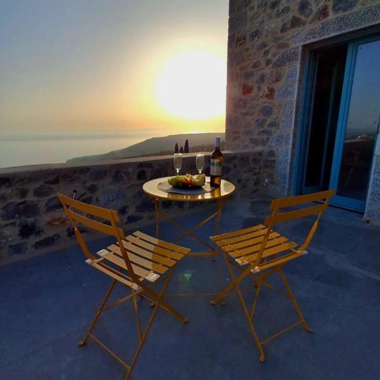 two chairs and a table with a bottle of wine at Ελαιόλιθοι Μάνη Villas 2 in Oitylo