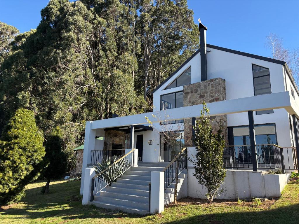 a white house with stairs and trees at Nest On Thula in Dullstroom