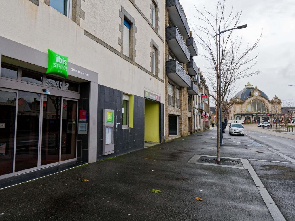 an empty street with buildings and a tree on the sidewalk at ibis Styles Saint Brieuc Gare Centre in Saint-Brieuc