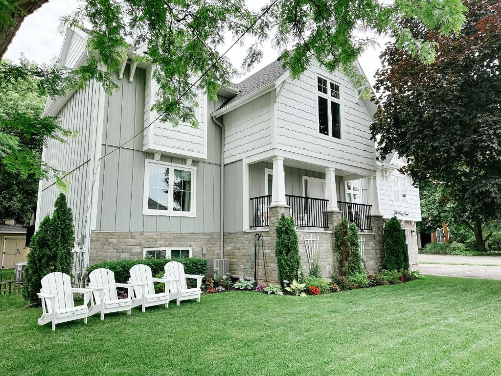 a white house with white chairs on the lawn at Inn On King Bed & Breakfast in Niagara-on-the-Lake