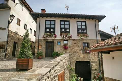 a stone house with windows and a stone wall at Apartamentos Casa de la Abuela in Potes