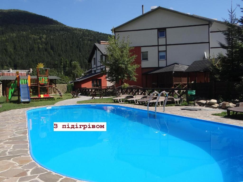 a large blue swimming pool in front of a building at Villa Provans in Tatariv