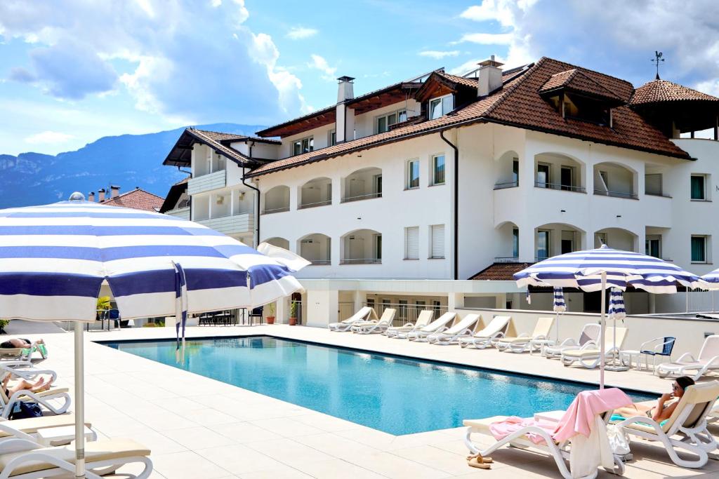 a hotel with a swimming pool with chairs and umbrellas at Hotel Markushof - Adults only in Auer