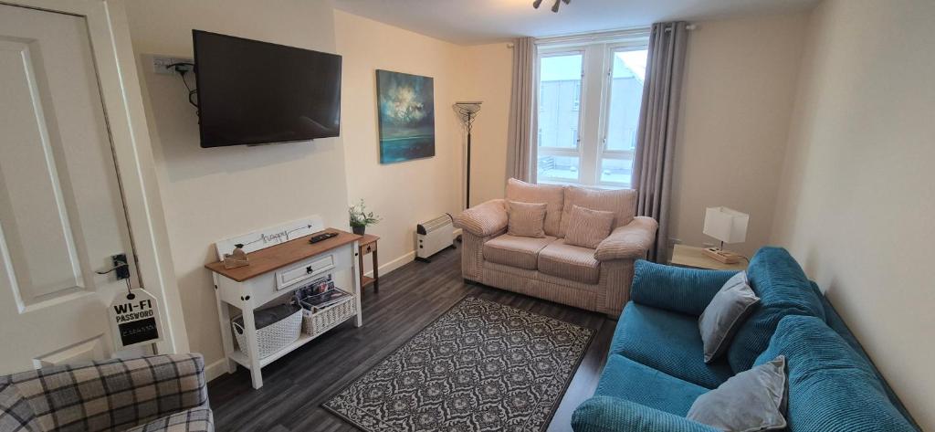 a living room with a blue couch and a tv at Flat 21 - 1st floor - Westview Terrace, Stornoway in Stornoway