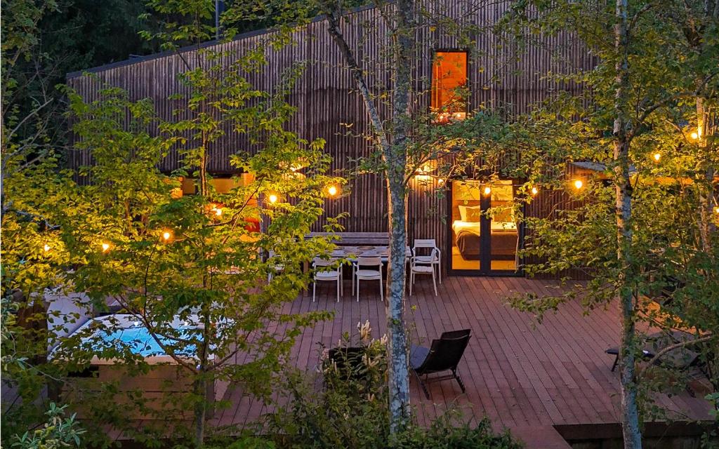 a patio with a table and chairs and lights at La Râu 663A - Riverside Mountain Chalet with Outdoor Jacuzzi in Porumbacu de Sus