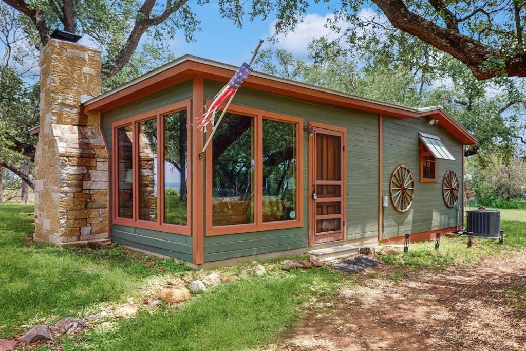 a green tiny house with a flag on it at Historic Lakefront & Wildlife Haven with Firepit & Gas Grill - Minutes to Water in Burnet