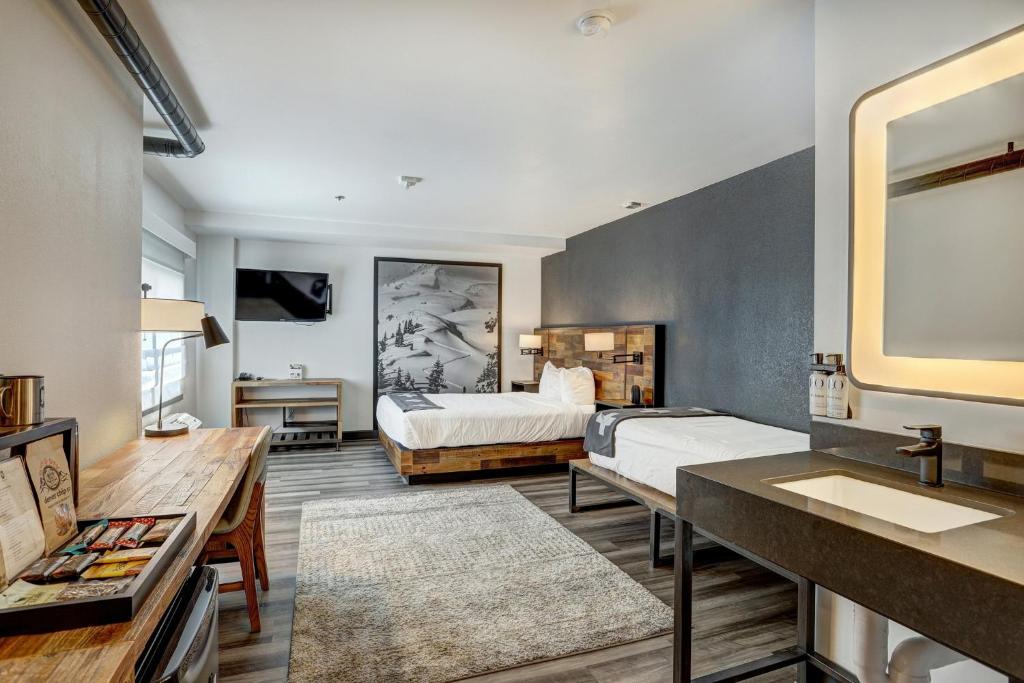 a bedroom with two beds and a sink and a mirror at Gravity Haus Breckenridge in Breckenridge