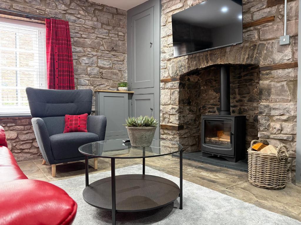 a living room with a fireplace and a couch and a table at 10 Crickhowell Cottages, Standard Street, Central Crickhowell in Crickhowell