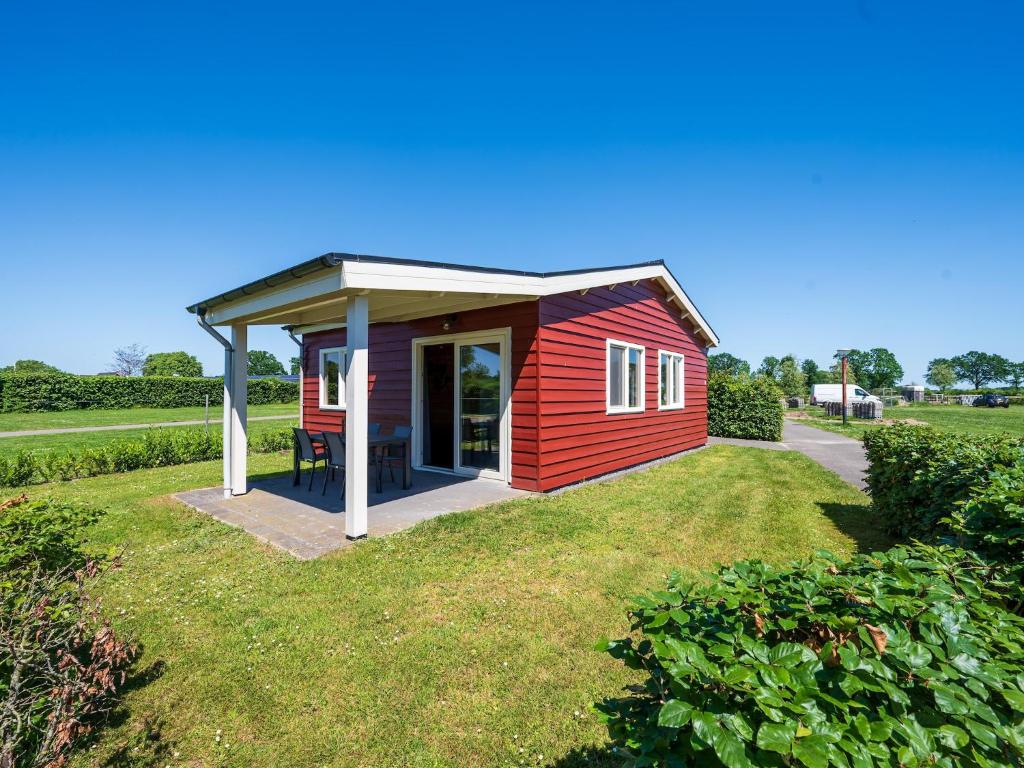 a small red shed with a roof on a lawn at Country Holiday home with shared pool in Someren-Heide