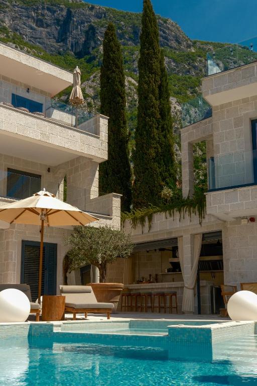 a hotel with a swimming pool with chairs and an umbrella at Mamei Boutique Villa in Dobrota