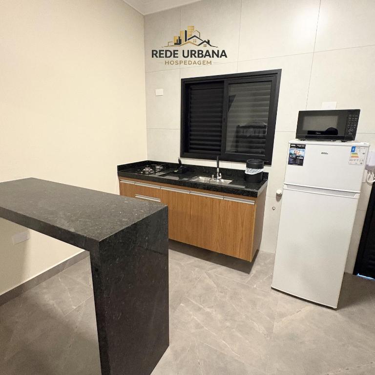 a kitchen with a counter and a refrigerator at Loft 7 com ar-condicionado da Rede Urbana in Indaiatuba