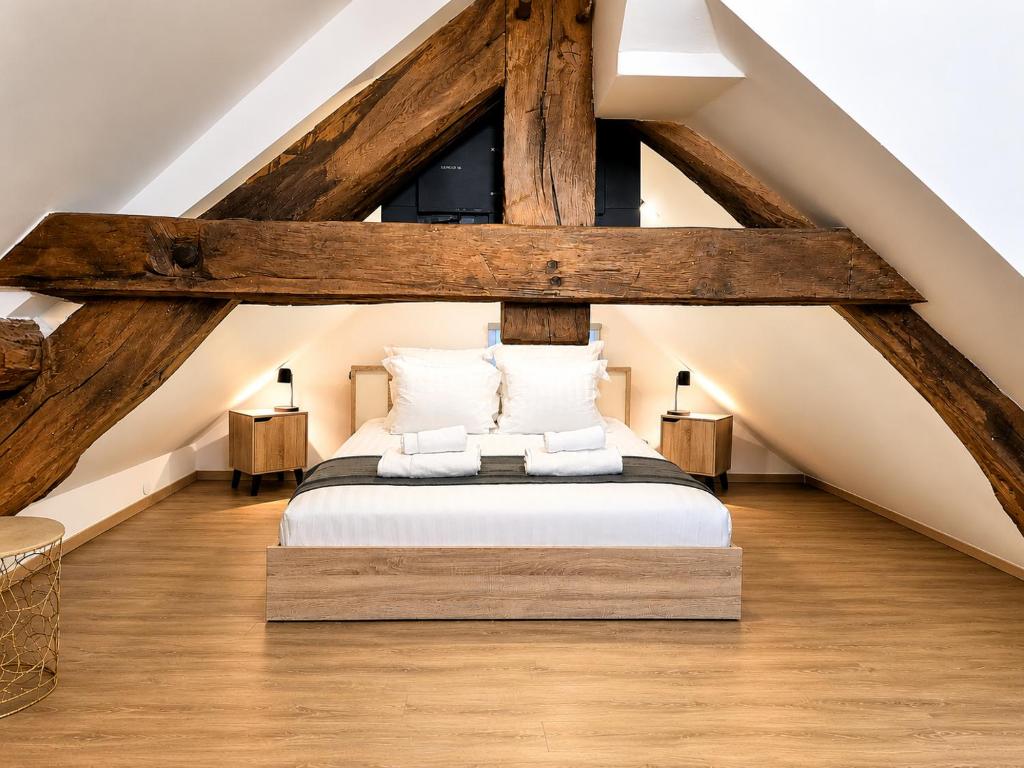 a attic bedroom with a bed and wooden beams at Suite Le Mans 70 in Pusey